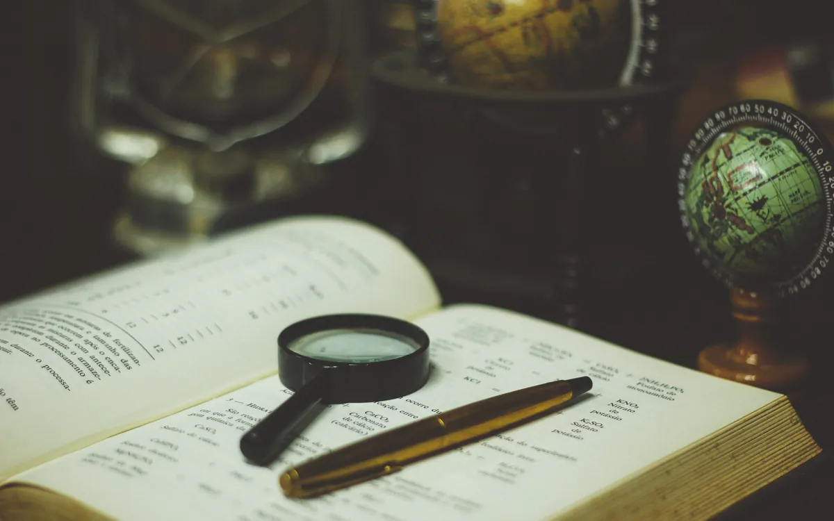 Magnifying glass and a fountain pen on an open book